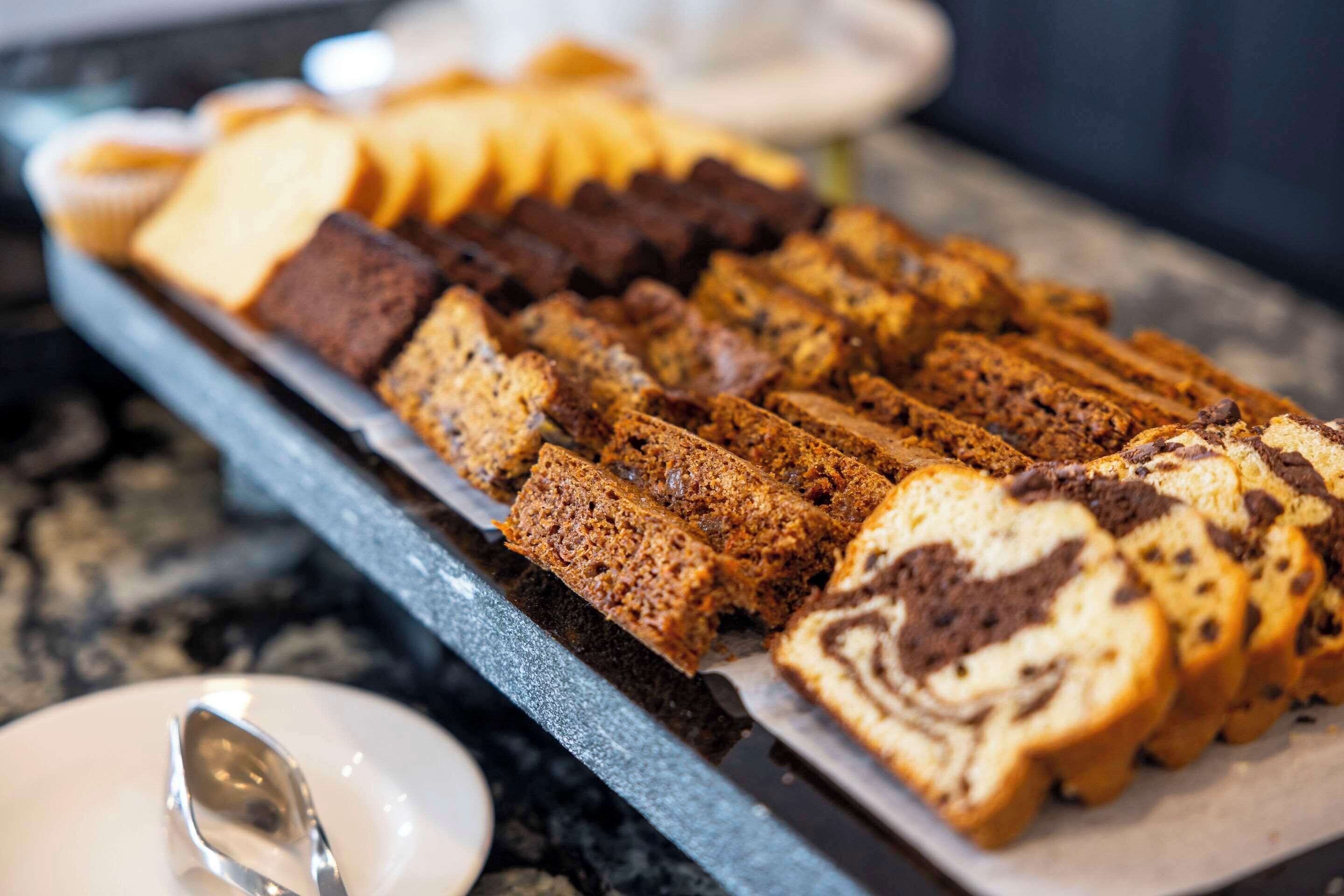 Un plateau rempli de diverses viennoiseries et de pains, posé sur un comptoir en marbre.