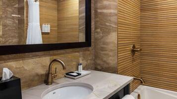 Un baño moderno con un espejo grande, un lavamanos y una bañera.