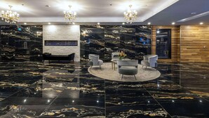 A lobby with a black marble floor, a reception desk, and a seating area with chairs and a table. - Halifax Tower Hotel & Conference Centre, an Ascend Collection Hotel (Halifax)