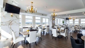 A spacious dining area with high ceilings, large windows, and modern chandeliers. - Halifax Tower Hotel & Conference Centre, an Ascend Collection Hotel (Halifax)