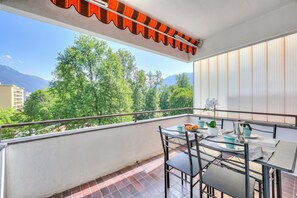 A balcony with a table, chairs, and a view of trees and mountains. - Lido Apartment Locarno With Balcony and Parking (Locarno)