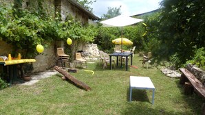 Un patio trasero con una mesa, sillas, un paraguas amarillo y una mesa blanca.