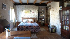 Un dormitorio rústico con una cama de madera, una estantería y un escritorio con un mapa.
