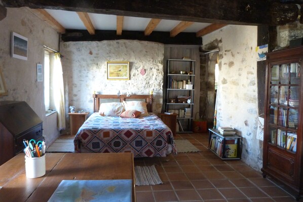 Un dormitorio rústico con una cama de madera, una estantería y un escritorio con un mapa.