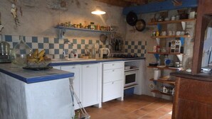 Una cocina con encimera azul, armarios blancos y salpicadero de azulejos, además de un colgador para ollas.