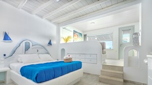 A modern bedroom with a white bed, blue bedding, and a small basket on the bed. - Bella View Mykonos Town Suites (Mykonos)
