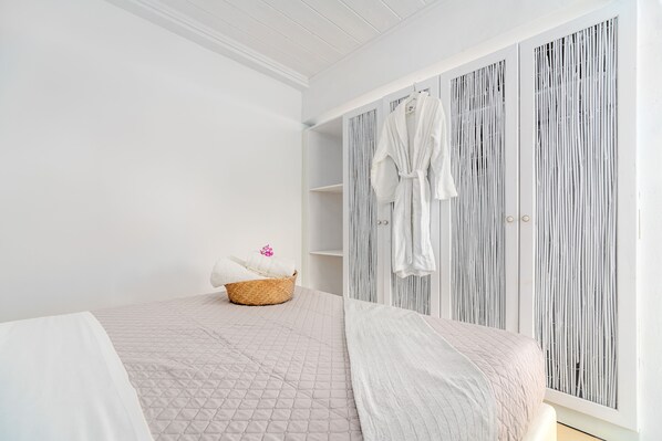 A bedroom with a bed, a bedside table, a wardrobe, and a window. - Bella View Mykonos Town Suites (Mykonos)