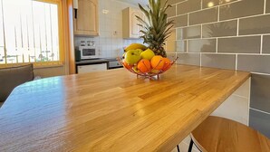 A kitchen with a wooden countertop, a fruit bowl with fruits, and a microwave.