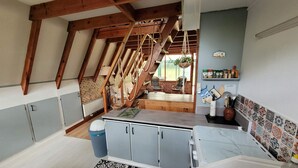 Eine Küche mit hohen Decken, freiliegenden Holzbalken und Blick in einen Essbereich.
