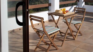A balcony with a table set for two, wooden chairs, and a view of the countryside. - Villa La Noria, 15 Pers, Pool, view of the ocean and the Andalusian mountains (AN)