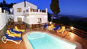 A modern villa with a swimming pool, multiple lounge chairs, and a wooden fence. - Villa La Noria, 15 Pers, Pool, view of the ocean and the Andalusian mountains (AN)
