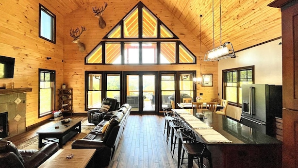 A log cabin interior with a dining area, kitchen, and seating space.