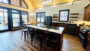 A spacious kitchen with wooden floors, a large island, and ample natural light from large windows.