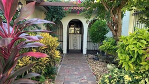 A pathway leading to a building with a tiled entrance and arched windows.