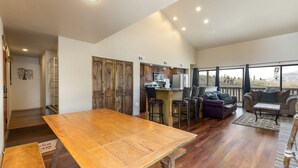 A spacious living area with a wooden dining table, a kitchen with modern appliances, and a balcony with a view. - Cozy Top Floor Condo w/ Incredible Mountain Views from Private Balcony! (Silverthorne)