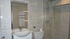 Un baño con lavamanos, inodoro y ducha.