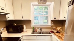 A compact kitchen with white cabinets, a stainless steel refrigerator, a microwave, and a sink.