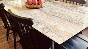 A dining table with a marble top surrounded by black chairs.