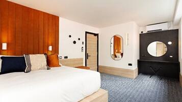 A hotel room with a bed, a wooden headboard, a mirror, a wardrobe, and a patterned floor.