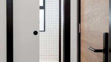 Un pasillo con una puerta de madera, suelo de baldosas y un tapete estampado.