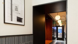 A hallway with a tiled floor, a framed motivational poster, and a door leading to a room with a wooden panel wall. - The Snug Townhouse (Galway)