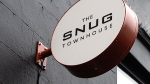 «The Snug Townhouse» -niminen kyltti on kiinnitettynä rakennuksen seinään.