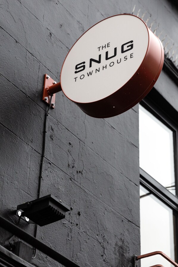 Letrero que dice 'The Snug Townhouse' colgado en la pared de un edificio.