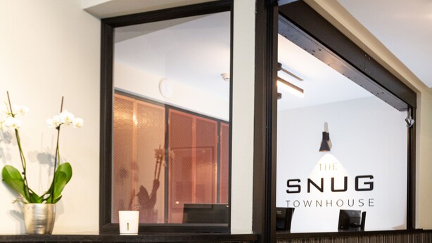 A reception area with a tiled wall, a potted plant, and a sign for 'The Snug Townhouse'. - The Snug Townhouse (Galway)