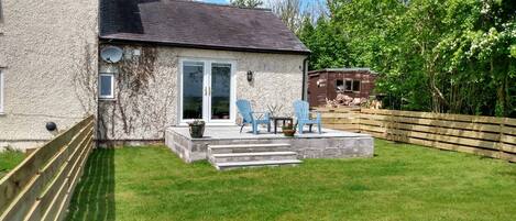 Een huis met een patio, een klein terras en een omheinde tuin.