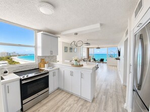 Una cocina moderna con vista a la playa, un comedor y una isla grande.
