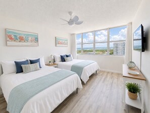 A hotel room with two beds, a ceiling fan, a large window with a view, and a flat-screen TV. - Beachfront 3 Bdrm Gem in Isla Verde  Walk 2 Eat (Carolina)