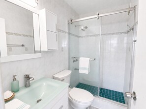 A bathroom with a glass-enclosed shower, a white toilet, a sink with a soap dispenser, and a towel rack. - Beachfront 3 Bdrm Gem in Isla Verde  Walk 2 Eat (Carolina)