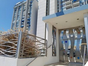 A modern building with a white facade, a metal gate, and a balcony with blue railings.