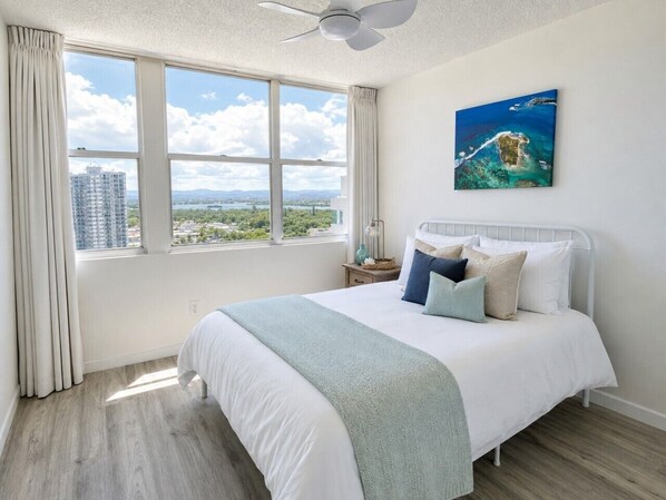 A bedroom with a large bed, a ceiling fan, a window with curtains, and a painting on the wall. - Beachfront 3 Bdrm Gem in Isla Verde  Walk 2 Eat (Carolina)