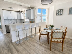 A modern kitchen with a central island, bar stools, and a dining table with chairs. - Beachfront 3 Bdrm Gem in Isla Verde Walk 2 Eat (Carolina)