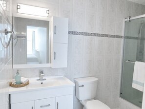 Une salle de bain avec un meuble-lavabo blanc, des toilettes et une douche à parois de verre.