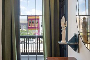 Enjoy a view of the city from the large window, framed by green curtains and a decorative hand-shaped detail.