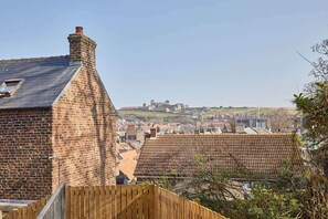 Un quartier résidentiel avec des maisons en briques, une clôture en bois et une vue lointaine d’une structure ressemblant à un château.