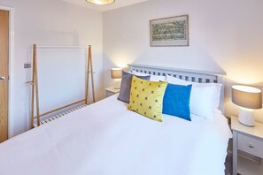 Ein Hotelzimmer mit einem Bett, zwei Nachttischen, einem Wandbild und einer Tür mit Heizkörper.