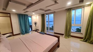 A bedroom with a large bed, a sliding glass door to a balcony, and a view of the sea. - Stay.Plus APA Apartments Nyali (Mombasa)