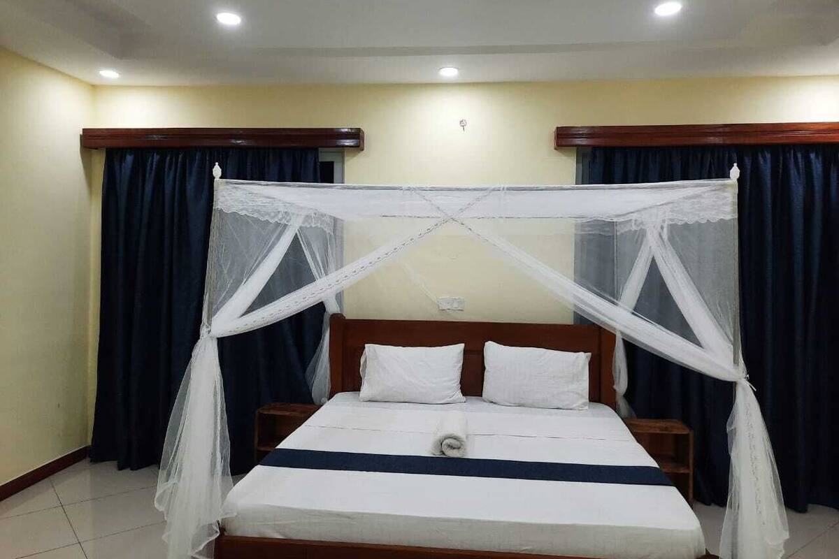 A single bed with a canopy, wooden headboard, and white bedding.