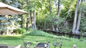 Eine Terrasse im Freien mit Tisch, Stühlen, einer Weinflasche und einem kleinen Blumentopf.