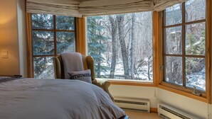 Ein Schlafzimmer mit großem Fenster, einem Bett, einem Sessel und einer Heizung.