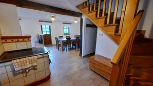 Un'ampia cucina con una scala in legno, un'area pranzo con sedie e vista sul soggiorno.