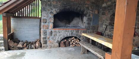 A rustic stone fireplace with a bench and firewood storage.