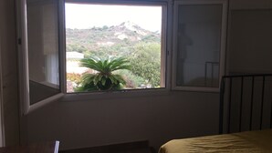 A bedroom with a window overlooking a hillside.