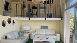 A modern living room with a white sofa, a coffee table, and a balcony with a railing.