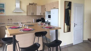 A kitchen with a wooden table set for four, a white refrigerator, and light-colored cabinets.