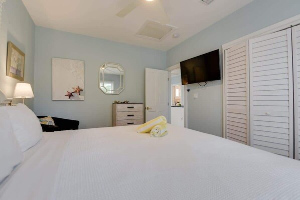 Une chambre d’hôtel comprenant un lit, un téléviseur fixé au mur, un miroir et une armoire.