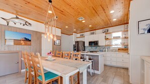A spacious kitchen with wooden cabinets, a central island, and a dining area with wooden chairs and a table. - Gorgeous, pet friendly, coastal cottage within walking distance to the restauran (Port Aransas)